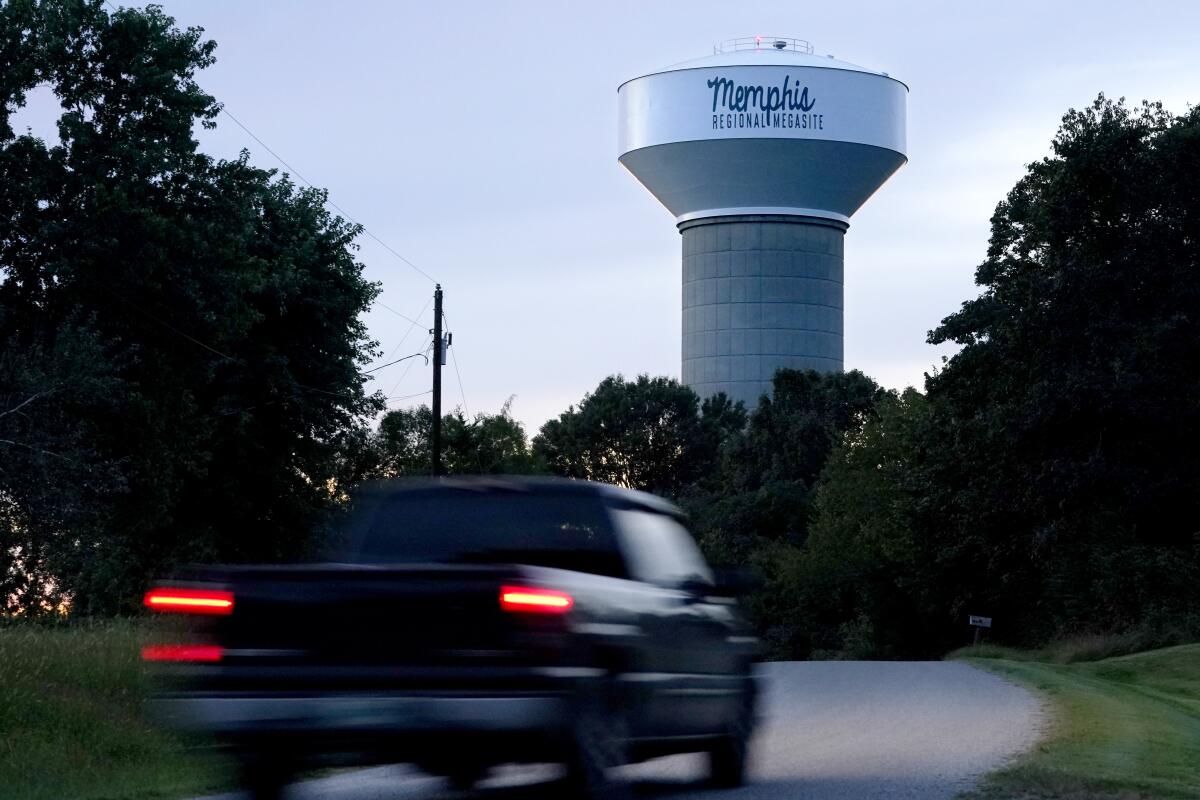 A truck speeds by on a road toward a water tower.
