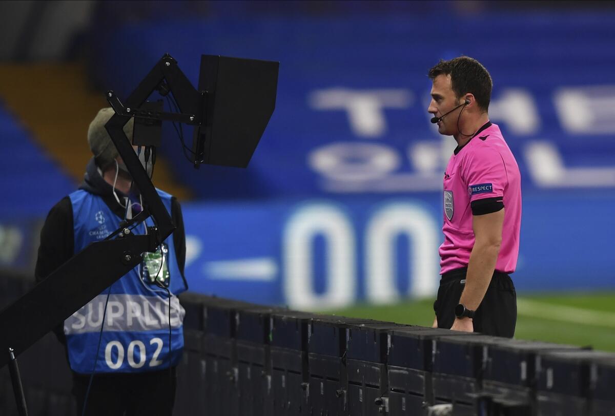 A referee watches an incident on the VAR screen before awarding a penalty to Chelsea during the Champions League Group E soccer match between Chelsea and Rennes at Stamford Bridge, London, England, Wednesday Nov. 4, 2020. (Ben Stansall/Pool via AP)
