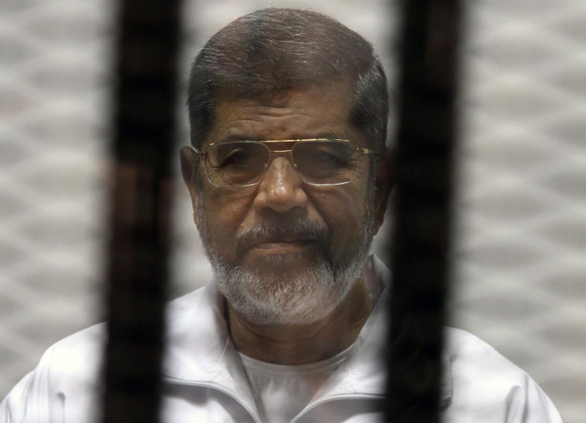 Ousted Egyptian President Mohamed Morsi in the defendant's cage during a court appearance in May. Egyptian authorities have added new charges against Morsi, alleging he gave state secrets to Qatar.