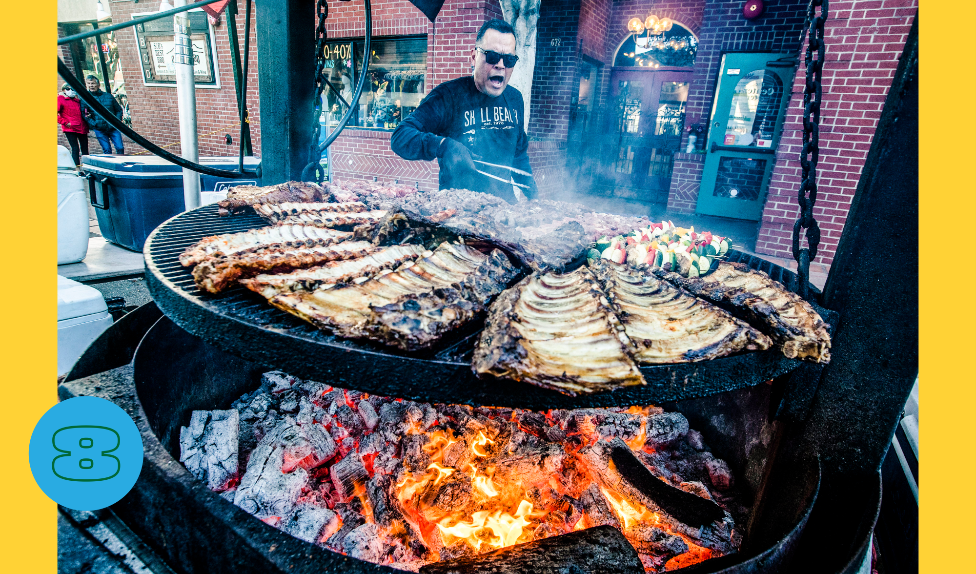 Chef Victor Albarron tends the F. McClintocks barbecue pit, full of ribs and other meats, at an outdoor market.