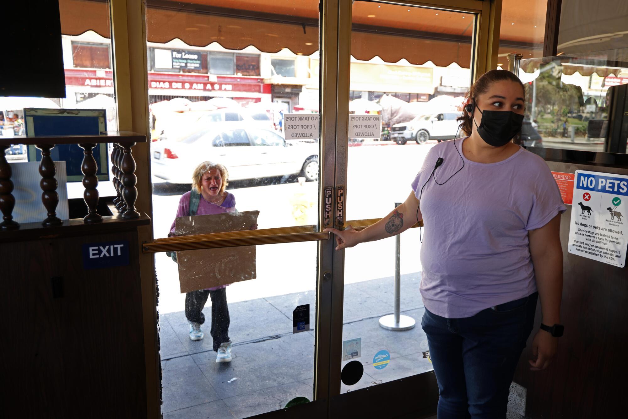 Rosalinda Romero stands near the front door inside Langer's as a woman approaches outside.