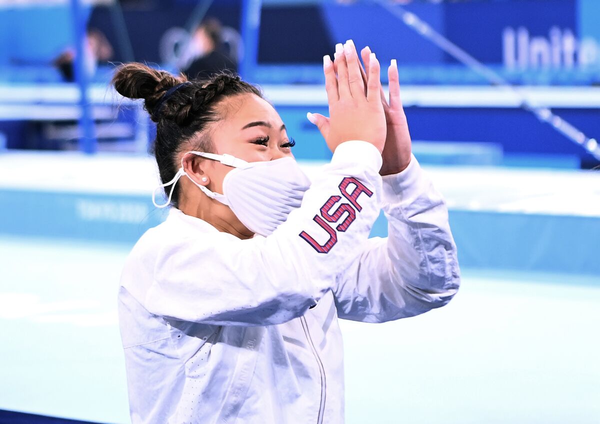 Olympic gold medalist Sunisa Lee claps in a white Team USA exercise suit