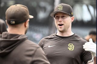 El primera base de los Padres de San Diego Jake Cronenworth habla con su compañero durante el calentamiento antes del juego de inicio de temporada ante los Rockies de Colorado el jueves 30 de marzo del 2023. (AP Foto/Alex Gallardo)