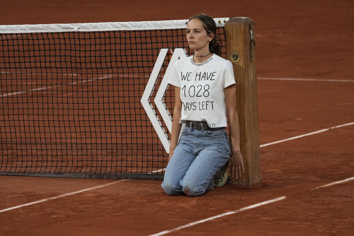 A woman protests at the net while Marin Cilic plays Casper Ruud in the French Open semifinals June 3, 2022, in Paris.