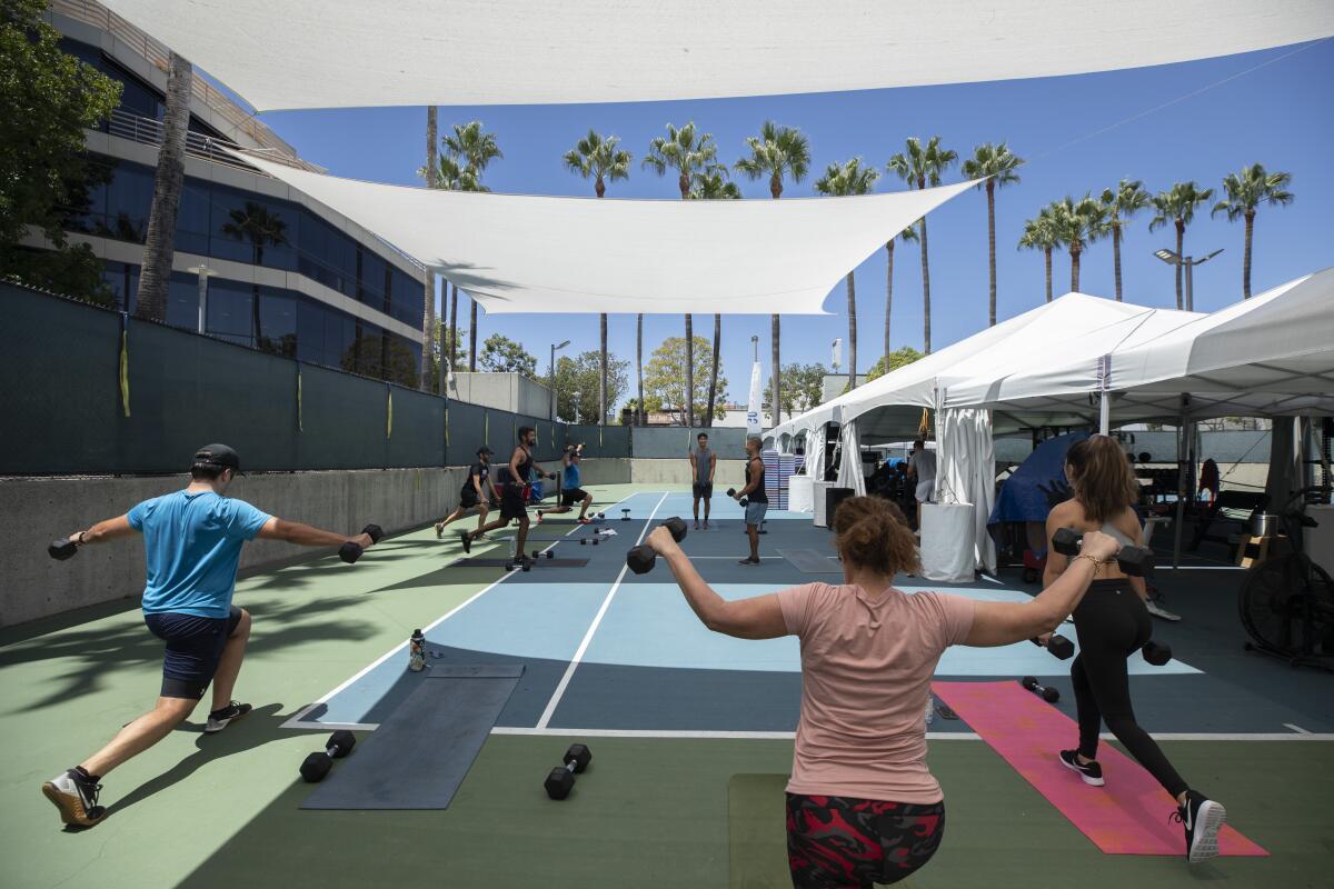 People lift weights during an outdoor exercise class