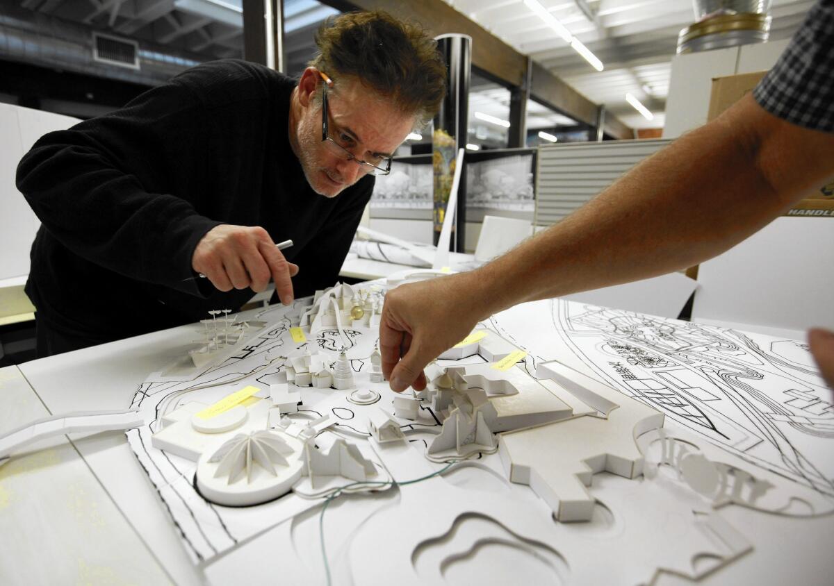 Michael Hood of Gary Goddard Entertainment, left, watches as Bob Baranick, adjusts a building on an amusement park model. Half the work that Goddard and his designers have done in the last few years has been for theme parks and resorts in Asia and the Middle East.