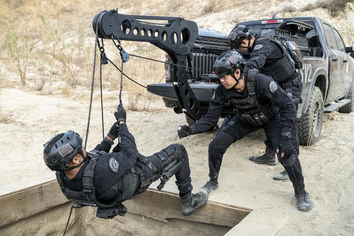 Shemar Moore is lowered on a winch as David Lim watches in "S.W.A.T." on CBS.