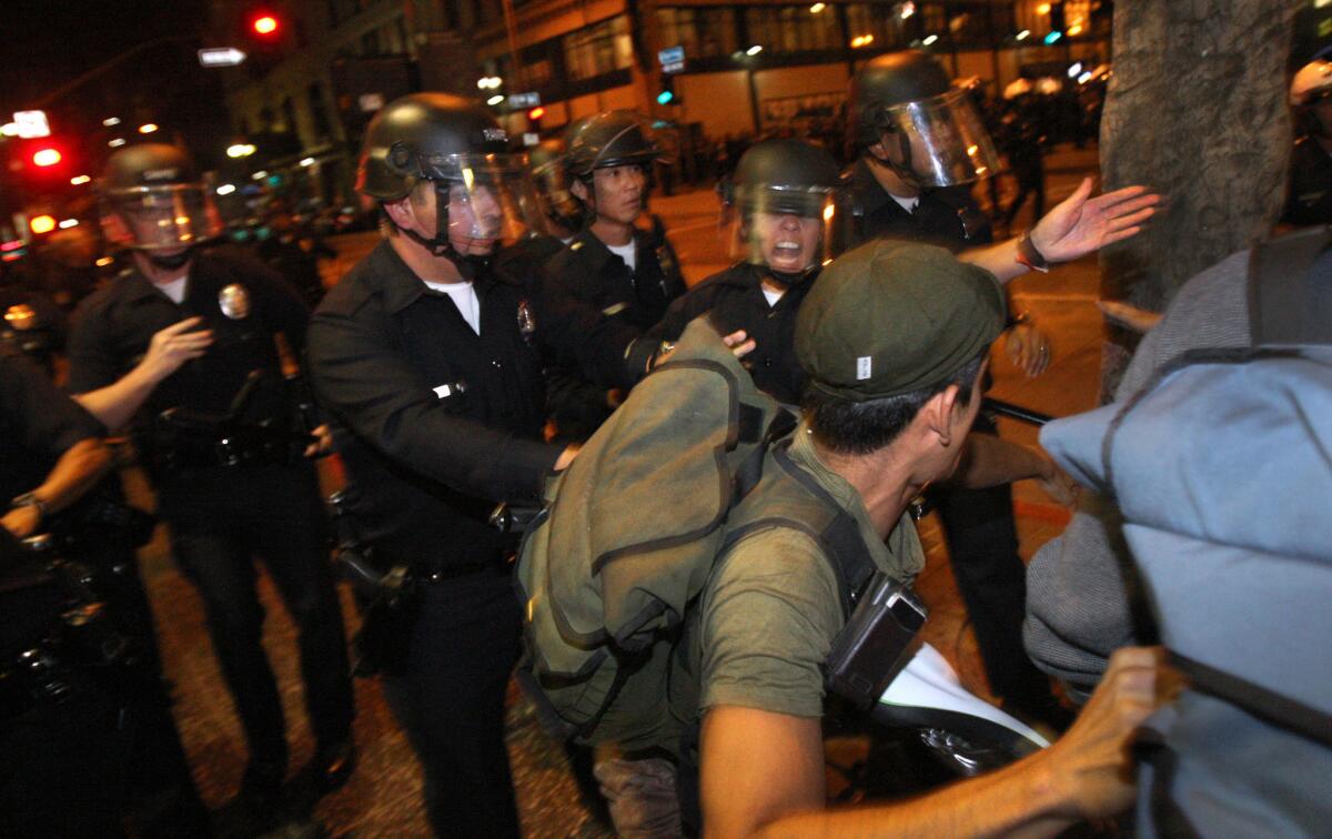 Los Angeles police in riot gear disperse a crowd of Occupy L.A. protesters in a July 2012 protest. City officials approved a multi-million dollar settlement with protesters who claim their rights were violated by the LAPD's military tactics in 2011 clashes.