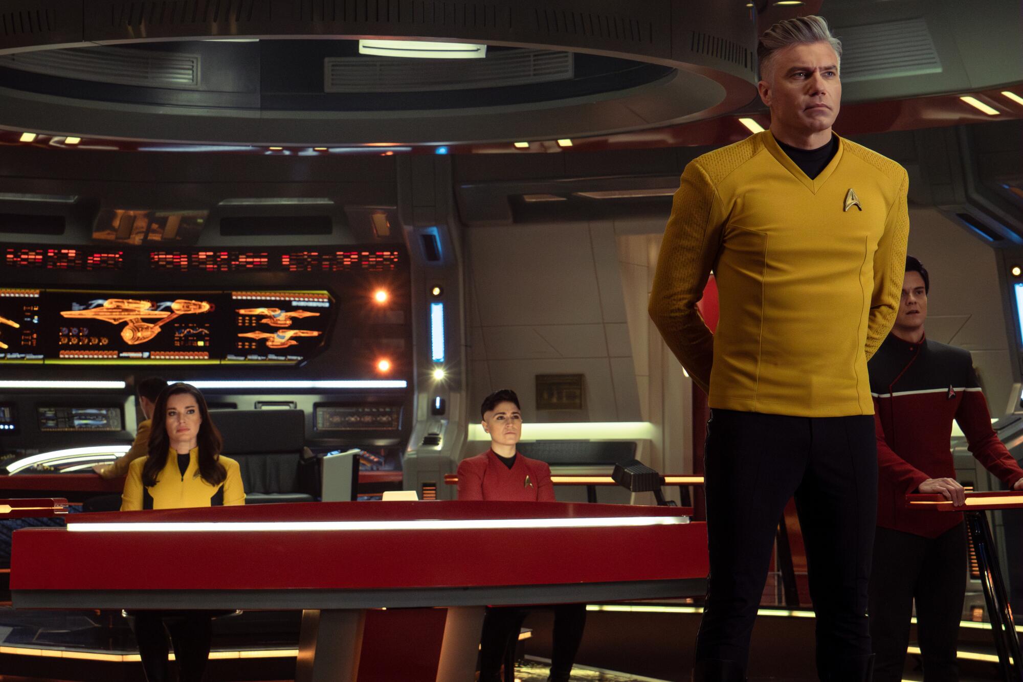 Three seated officers and the standing captain on the bridge of a starship
