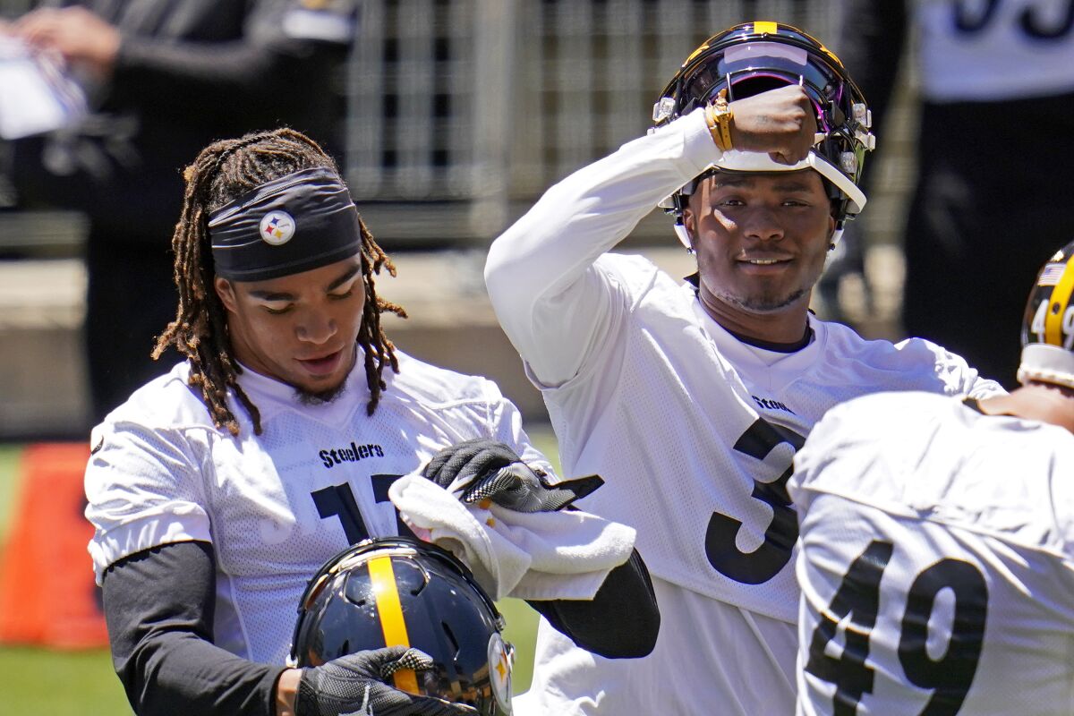 Pittsburgh Steelers quarterback Dwayne Haskins, center, and wide receiver Chase Claypool, left, take a break during the team's NFL mini-camp football practice in Pittsburgh, Wednesday, June 16, 2021. (AP Photo/Gene J. Puskar)