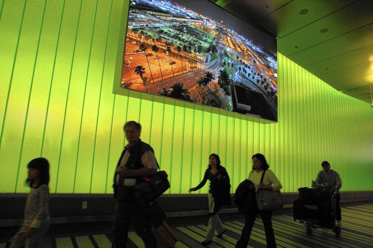 Travelers arrive at the Tom Bradley International Terminal where they are greeted by high-tech lighting and a video screen.