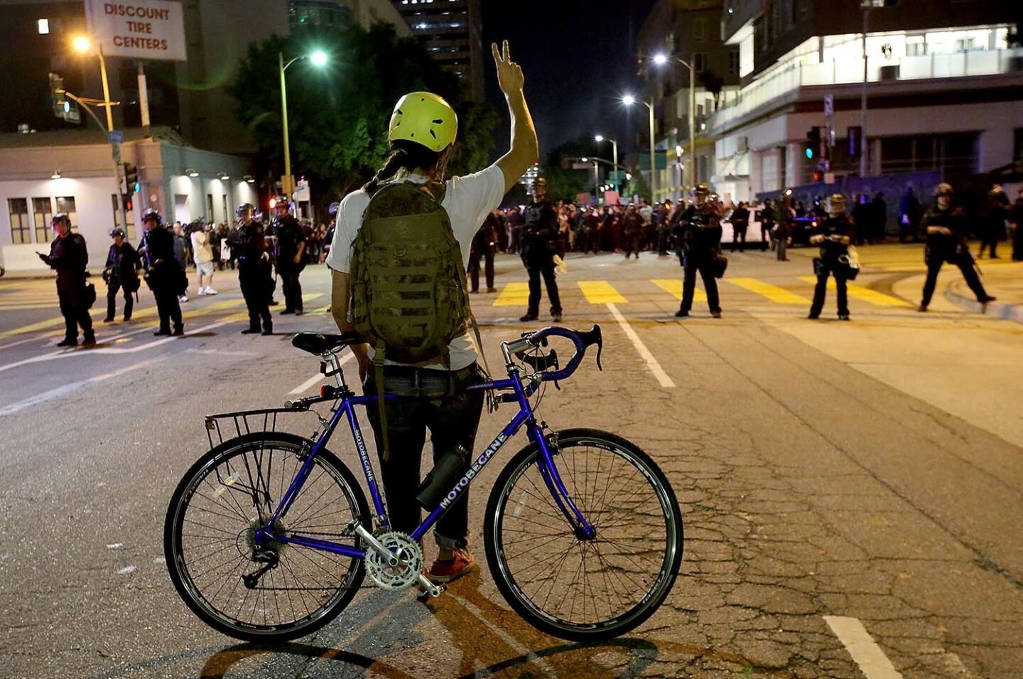 A protester waves the peace sign to LAPD officers blocking the intersection of Olive Street and Olympic Boulevard during an anti-Trump march through downtown Los Angeles.