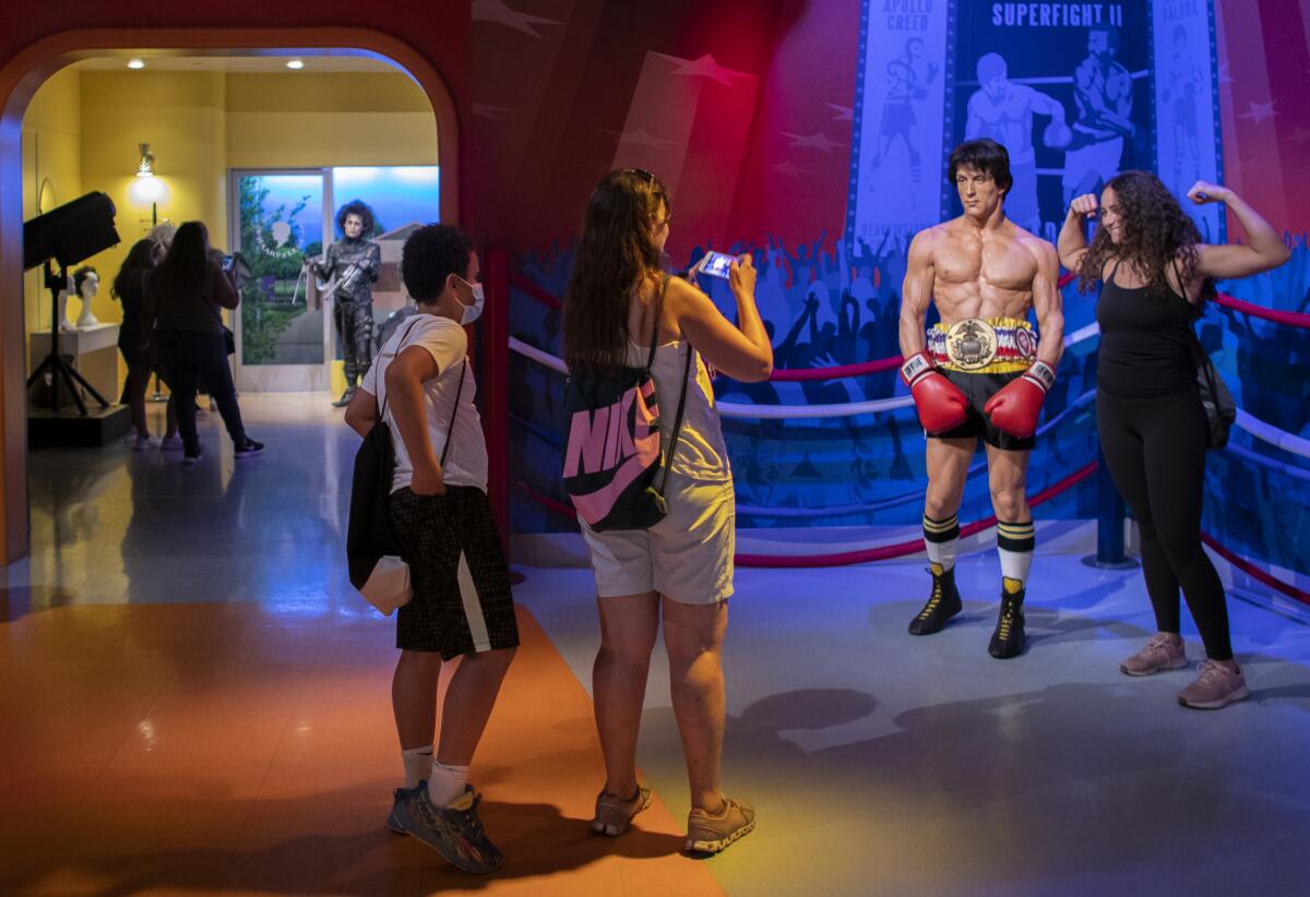 A tourist poses next to a wax figure. 