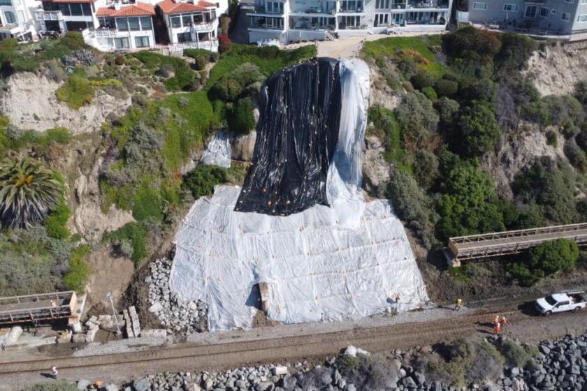 Plastic sheeting covers the hillside where a landslide has stopped passenger trains from traveling at San Clemente.