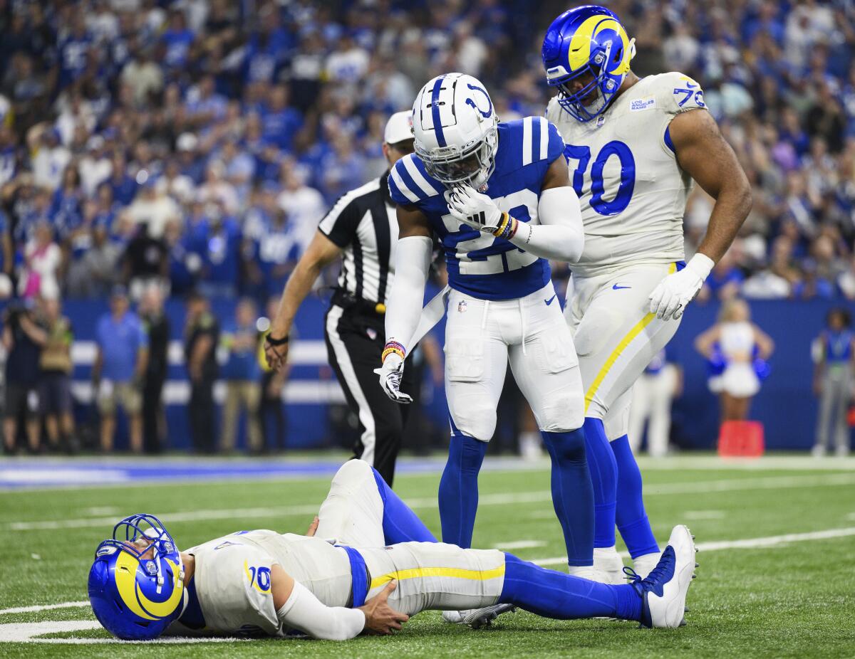 A Colts player offers a hand to Matthew Stafford, who lies flat on the turf