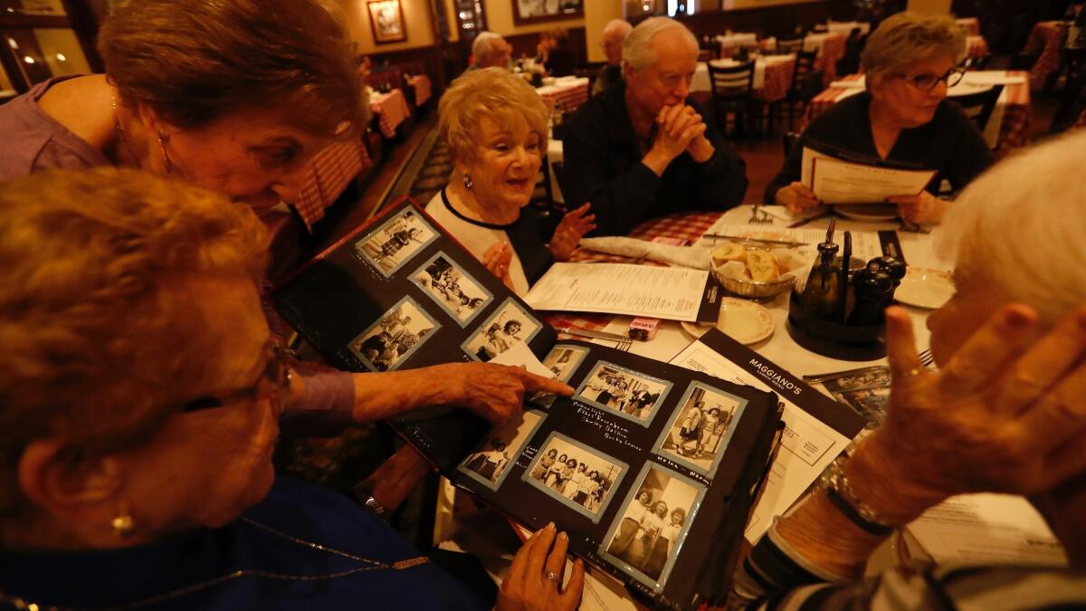 Armony Share, 86, top left, shows Arlene Dunaetz, 85, bottom left, photographs from their high school days in 1950 during a lunch at Maggiano's Little Italy restaurant in Woodland Hills.