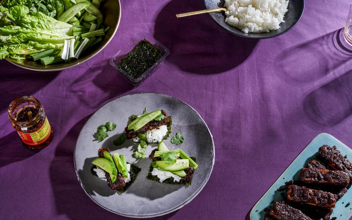 Two plates hold strips of baked tofu in a dark brown sauce.