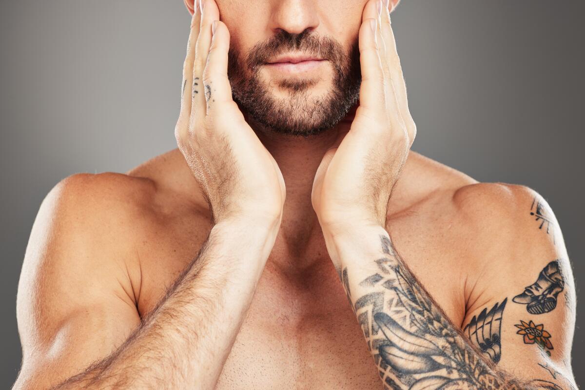 Beauty, skincare and body with a man model in studio on a gray background with an arm tattoo 