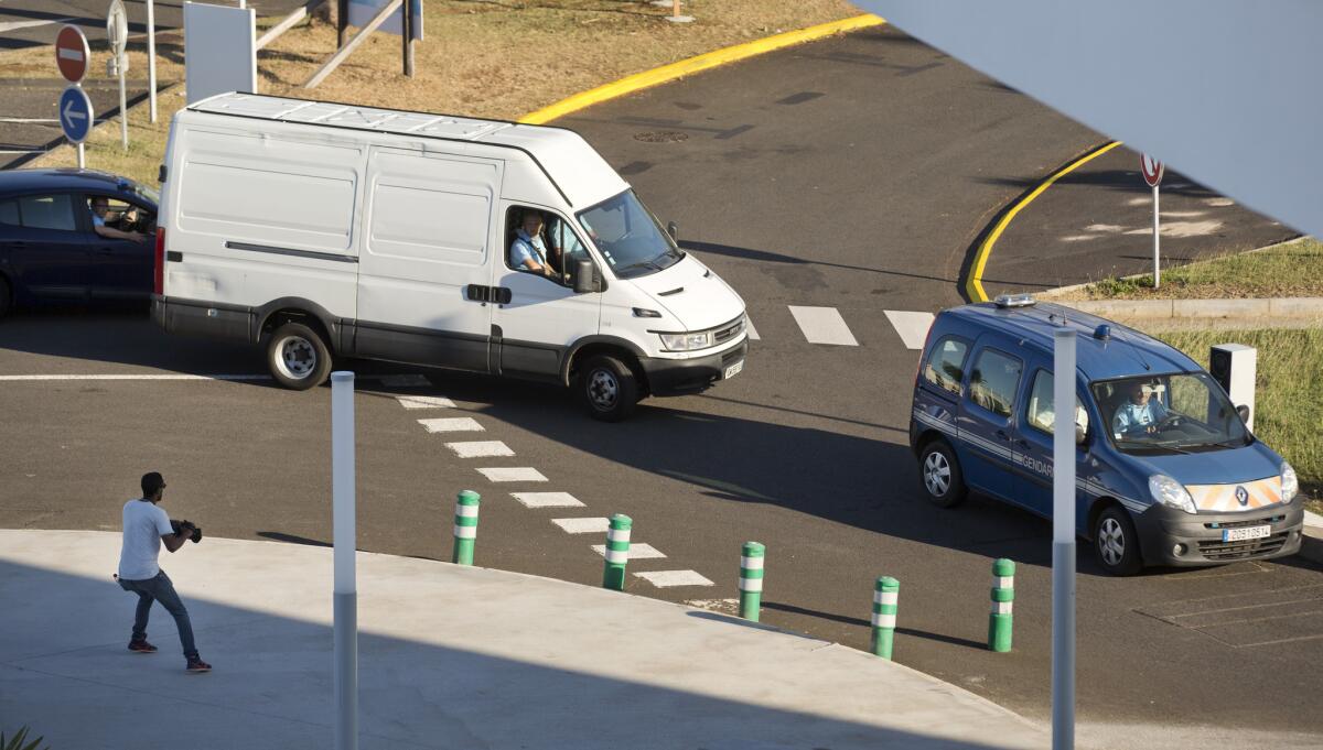 A white van carrying the airplane wing part that washed up on Reunion Island is escorted by the French gendarmerie to a cargo hangar at the island's Roland Garros Airport in Sainte-Marie on July 31.