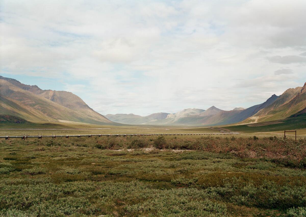 A view of a wide open valley is intersected by a pipeline.