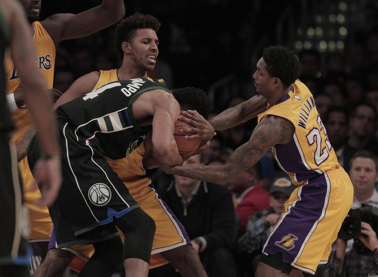 Los Angeles Lakers forward Nick Young (0) and guard Lou Williams (23) force a jump ball after tying up Milwaukee Bucks forward Giannis Antetokounmpo in the first half at Staples Center on Tuesday.