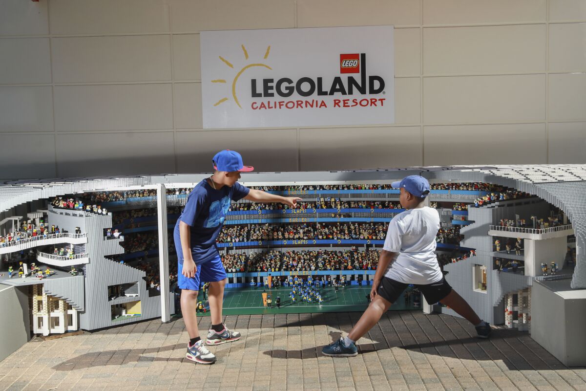 Two children stand outside the Lego replica of SoFi Stadium. 