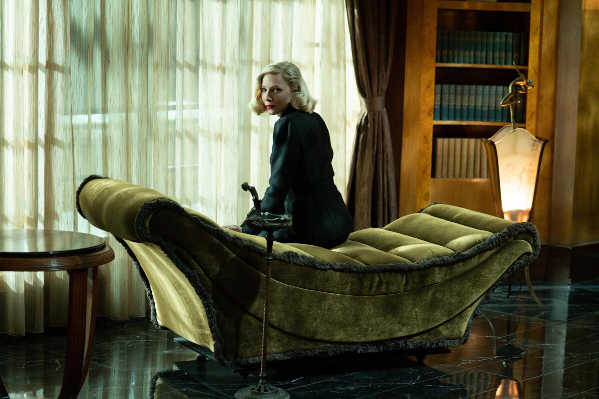 A woman sits on a green velvet psychiatrist's couch, looking over her shoulder.