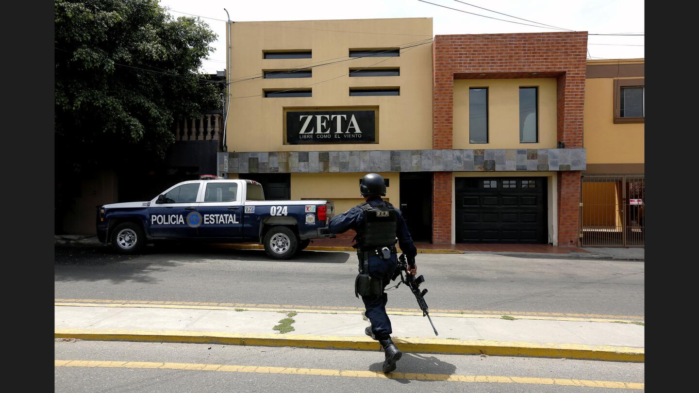 Baja California state police stand guard outside the offices of Tijuana's Zeta newspaper, a weekly investigative publication. Zeta has received recent threats from Mexican drug trafficking cartels for their reporting on crime. There has been a recent increase in homicides in Tijuana because of cartels fighting over the local drug market.
