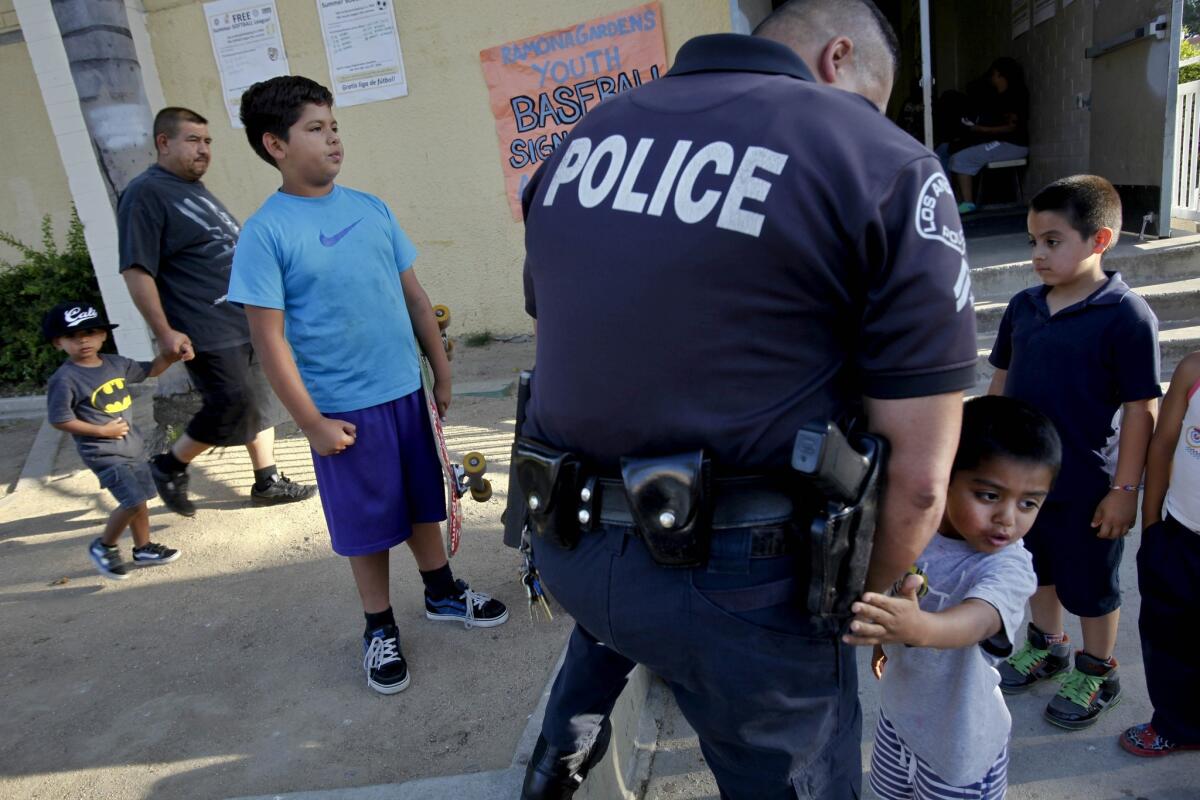 LAPD Officer Clem Toscano plays with kids outside a community meeting at the Ramona Gardens Recreation Center to address a fireboming some say was racially motivated.