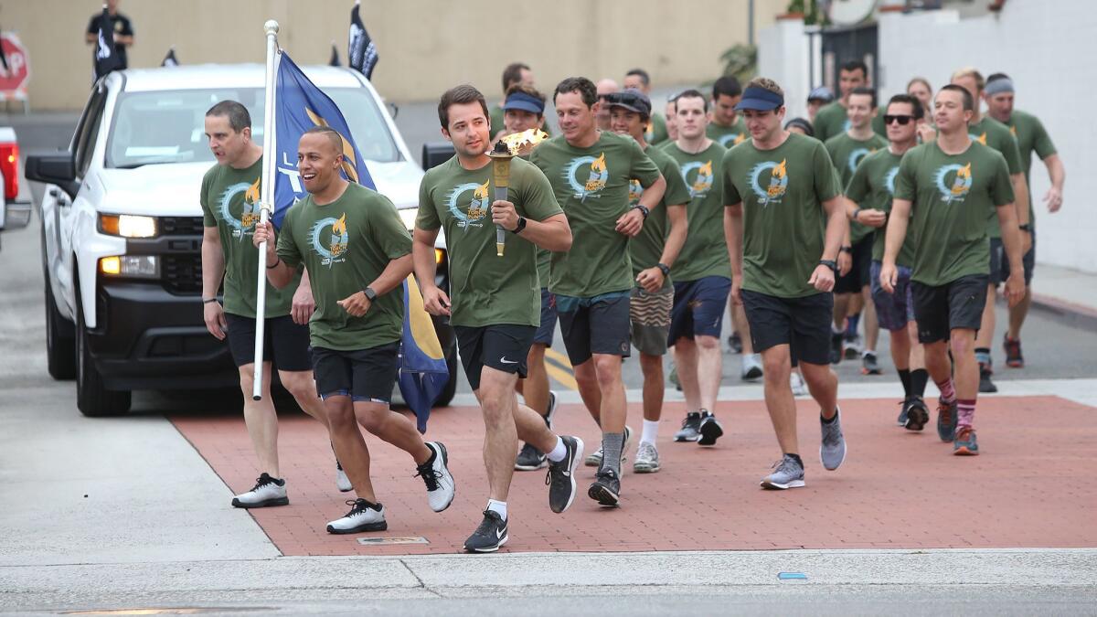 Laguna Beach police officers and lifeguards turn onto Forest Avenue in Laguna as they begin their portion of the Law Enforcement Torch Run for Special Olympics Southern California on Thursday morning.