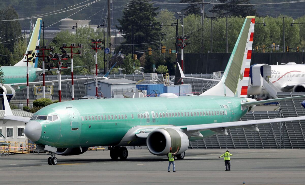 FILE - In this May 8, 2019, file photo workers stand near a Boeing 737 MAX 8 jetliner being built for American Airlines prior to a test flight in Renton, Wash. American Airlines CEO Doug Parker says his airline is feeling more confident that its grounded Boeing 737 Max jets will soon be approved to fly again. (AP Photo/Ted S. Warren, File)