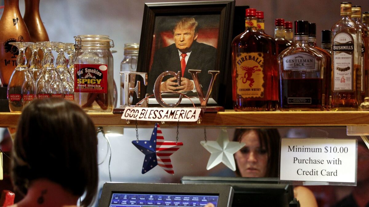 A picture of President Donald Trump sits on a shelf above a cash register as bartender Erin Smidt puts in an order.