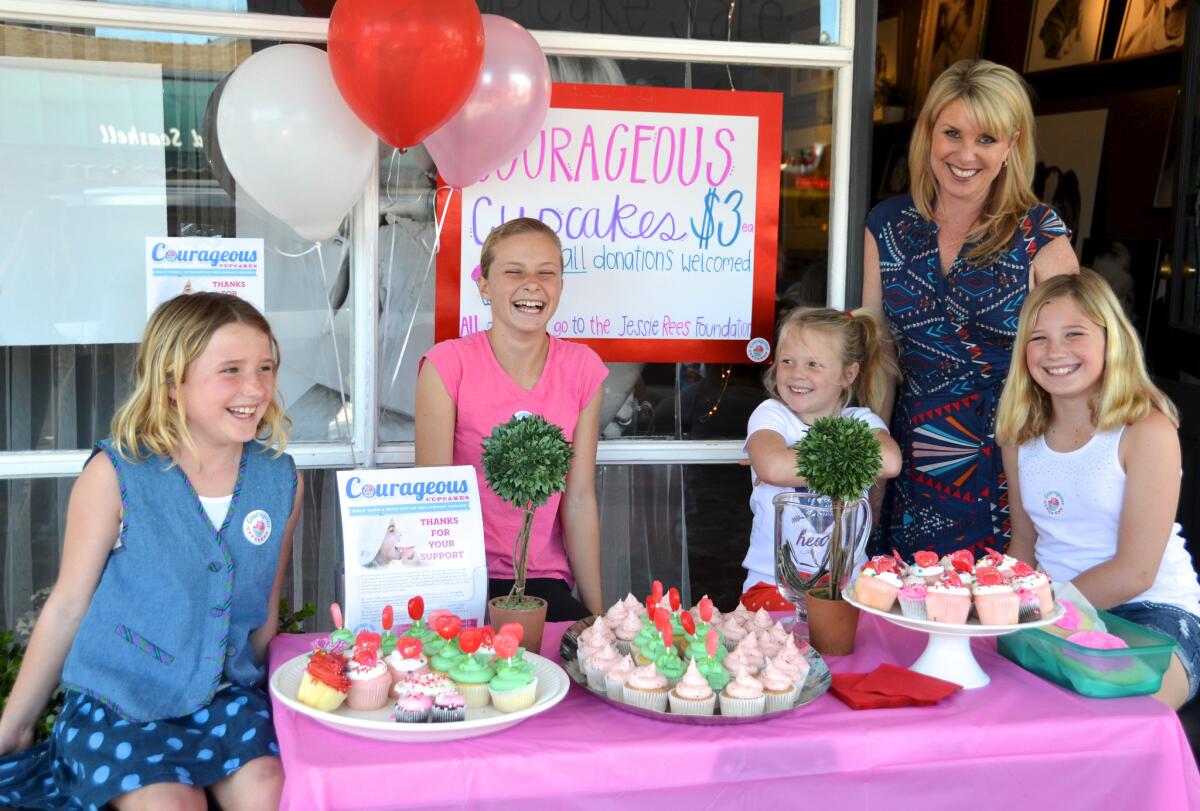 Newport Elementary students, seated from left, Sadie Walshe, Lola Sinacori, Alli Baron, Tess Walshe, and Classic Kids manager Michelle Tingler, set up Courageous Cupcakes stand in front of Classic Kids Photography Store on Balboa Island.