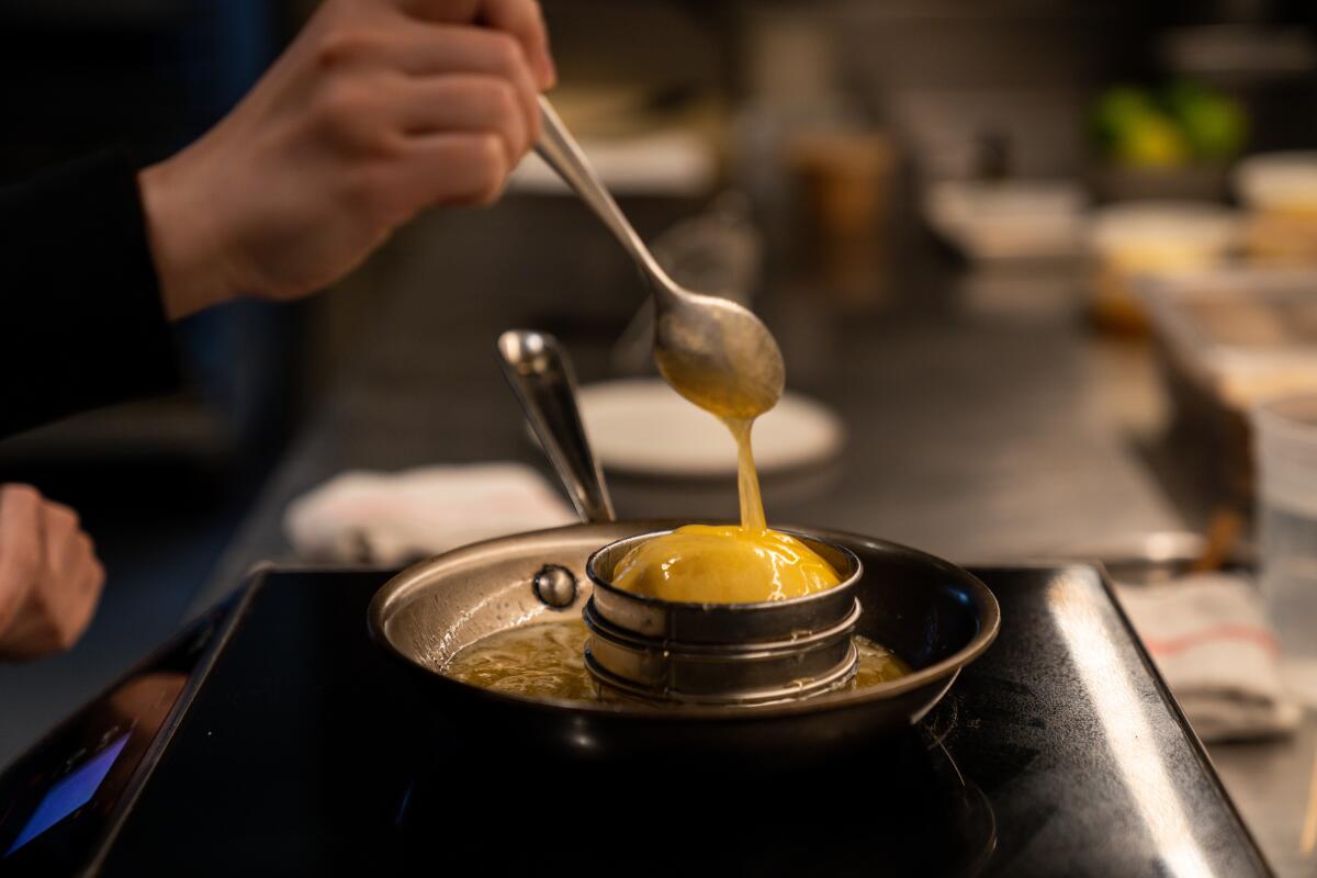 Honey butter pours from a spoon over dough in a ring mold in a skillet.
