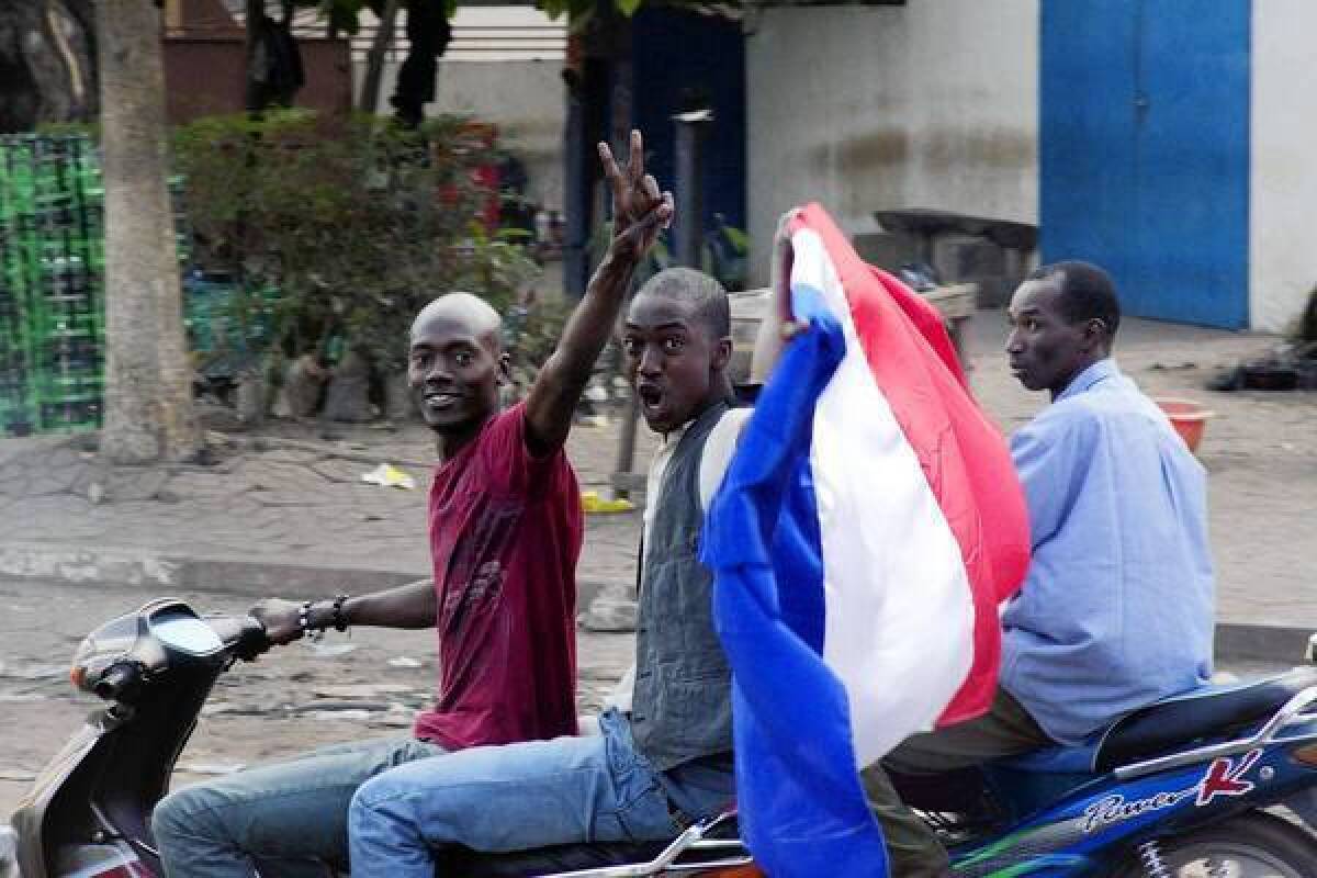 People wave a French flag in Bamako, Mali. France has sent troops and launched airstrikes to help Malian forces hold back an advance by Islamist rebels.