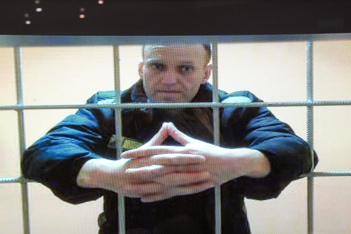 FILE - In this image provided by the Russian Federal Penitentiary Service, opposition leader Alexei Navalny appears on a video screen set up at Moscow City Court, on May 24, 2022. Russian opposition leader Alexei Navalny says prison officials ordered him to serve at least three days in solitary confinement, citing a minor infraction, in retaliation for his activism behind bars.(Russian Federal Penitentiary Service via AP)