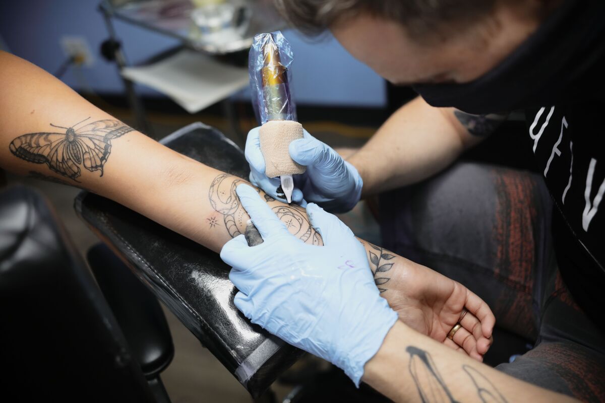 Eric Whitman works on a tattoo on Alexa DeFrazie.