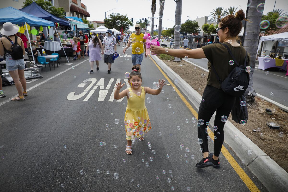 Elsie Carrillo entertains her daughter with a bubble maker at the Chula Vista Lemon Festival.