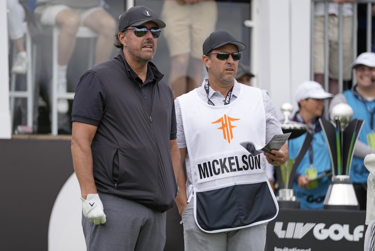 Phil Mickelson stands next to his caddie as he competes in the first round of the inaugural LIV Golf Invitational.