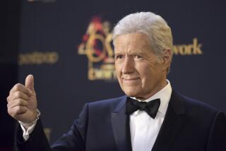 Alex Trebek gives a thumbs up with a look of assurance on his face while wearing a black tuxedo and bowtie 
