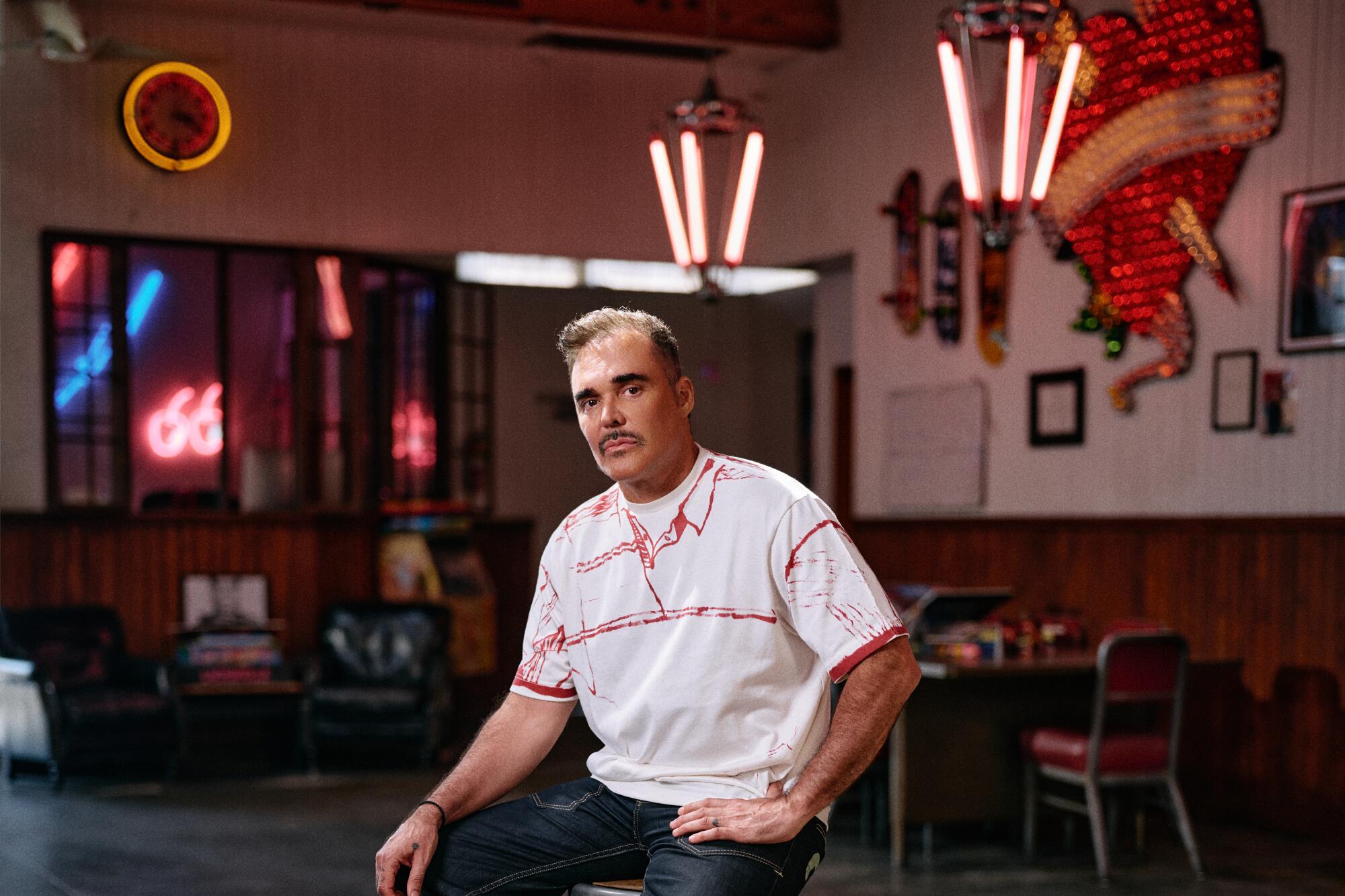 David LaChapelle sits on a stool in his studio.