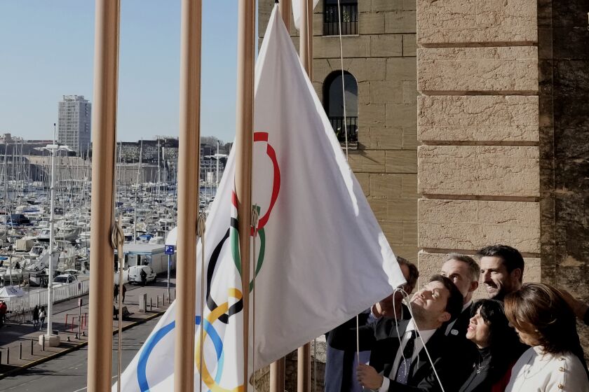 Mayor of Marseille Benoit Payan, center, raises the Olympic flag with Head of Paris 2024 Olympics Tony Estanguet, center right, after a press conference at the Marseille City Hall, southern France, Friday, Feb. 3. 2023. Instead of arriving overland, the symbolic flame alighting the Paris 2024 Games will take to the seas from its birthplace in Greece, arriving aboard a three-masted tall ship in the French port of Marseille. (AP Photo/Thibault Camus)