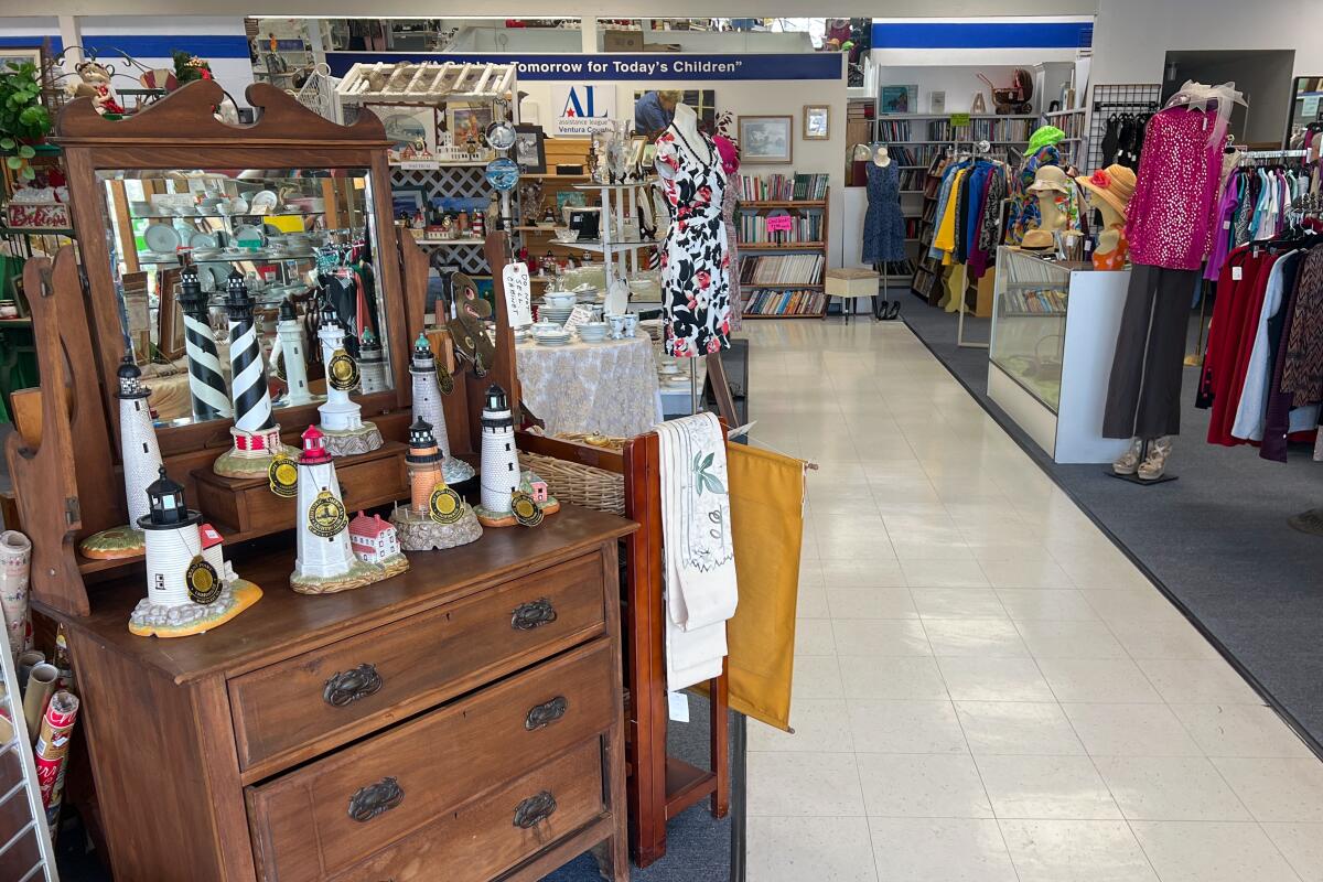 Furniture and clothing nicely arranged in a thrift store with wide aisles.