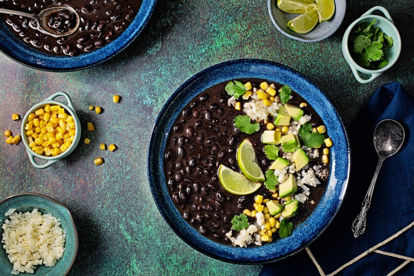 Black bean soup garnished with queso fresco, corn kernels and avocado.