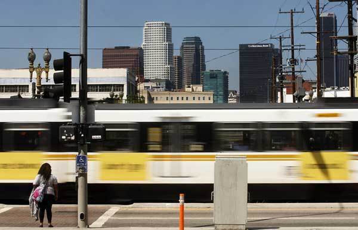A Metro Blue Line train zips past a pedestrian near Washington Boulevard and Flower Street. Metro is offering free fares Tuesday on all buses and trains.
