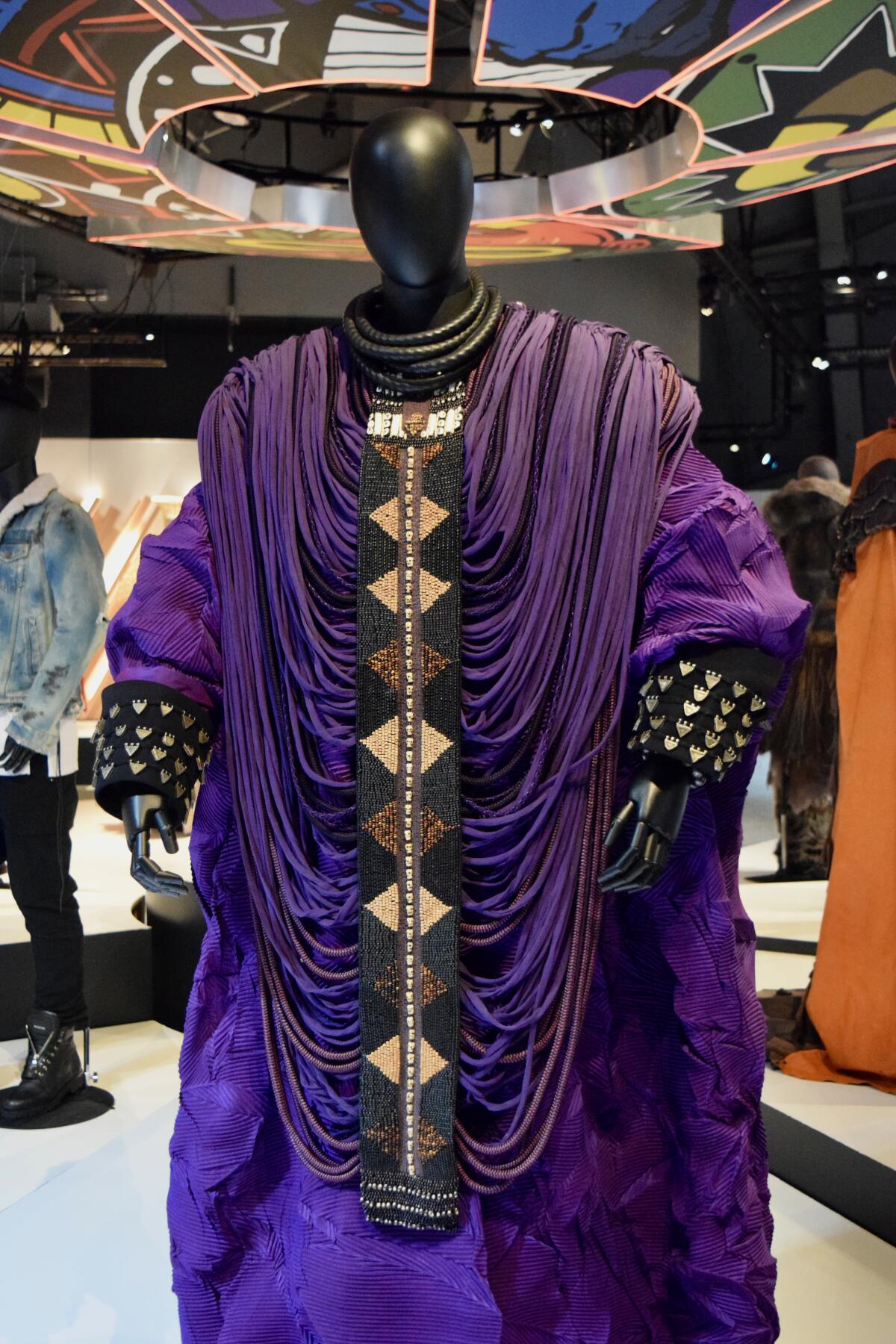 A big flowing purple costume with many please and golden buttons from a costume design exhibit.