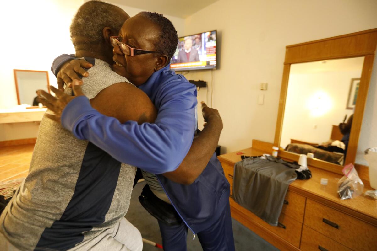 Two people embrace inside a motel room