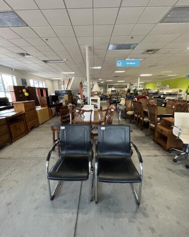 Two black chairs in a room full of office furniture