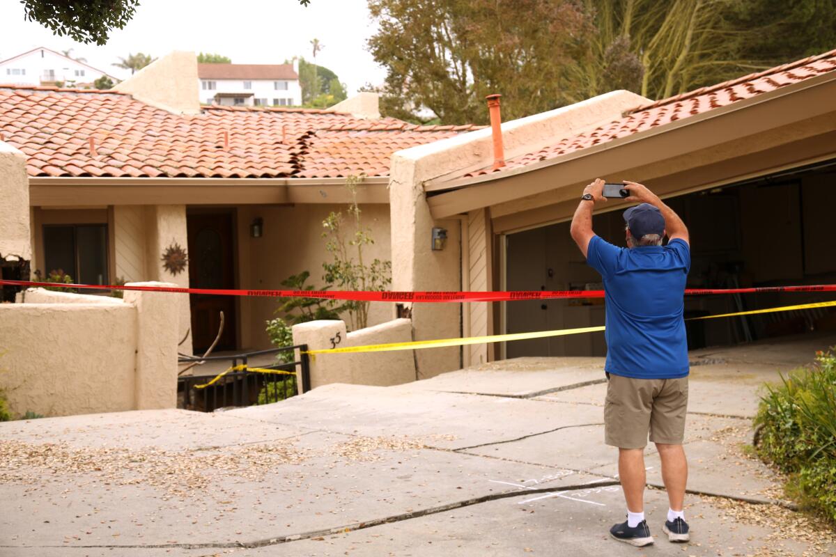 Rolling Hills Estates resident Bob Brown photographs a home with a cracked roof and yellow and red tape across the front.