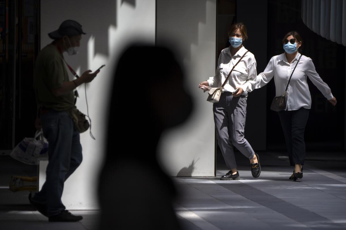 People in surgical masks walking through shopping and office complex